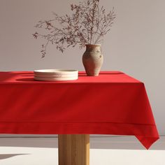 a red table cloth with a vase and plate on it