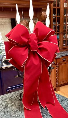 a red bow with two white candles sticking out of it's sides on top of a counter