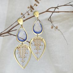 These Water Dew Drops Transparent Blue Resin Earrings are a delicate and elegant accessory, perfect for adding a touch of serenity to any look. The design features teardrop-shaped transparent blue resin pieces that evoke the purity of water droplets. Below, the open heart-shaped frame adorned with tiny golden chains and beads enhances the illusion of glistening dew. These earrings beautifully capture the essence of a fresh morning dew and are sure to charm those who appreciate nature-inspired jewelry.  The earrings dangle gracefully from gold-plated hooks, ensuring they are lightweight and comfortable for all-day wear. Whether you're dressing up for a special occasion or adding a unique flair to your everyday outfit, these resin earrings are sure to draw compliments and spark conversations Blue Pierced Drop Chandelier Earrings, Blue Dangling Beads Earrings For Wedding, Blue Wedding Earrings With Dangling Beads, Blue Teardrop Metal Chandelier Earrings, Blue Metal Teardrop Chandelier Earrings, Blue Danglers For Gift, Blue Teardrop Bohemian Crystal Earrings, Handmade Blue Drop Earrings, Blue Long Drop Chandelier Earrings As A Gift