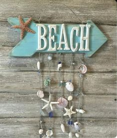 a wooden sign that says beach with shells and starfish hanging from it's sides