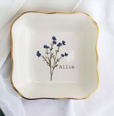 a white plate with blue flowers on it and the word alilie written in black