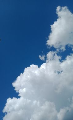 an airplane flying high in the sky with white clouds behind it and a blue sky