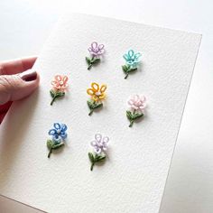 a person is holding a card with small flowers on it