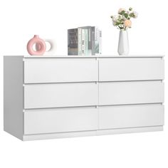 a white dresser with books and vases on the top, against a white background