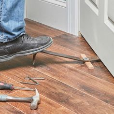 a person standing on top of a wooden floor next to hammers and pliers