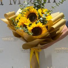 a bouquet of sunflowers is wrapped in brown paper and tied with a yellow ribbon