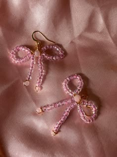 two pairs of pink beaded earrings sitting on top of a pink cloth covered surface