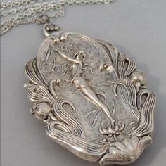 an old silver locke with a mermaid on it's face is sitting on a chain