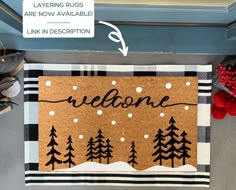 a welcome mat with the words welcome on it and pine trees in front of it