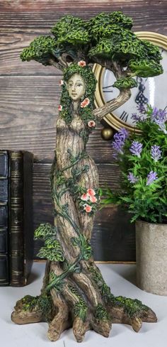 a statue of a woman with flowers on her head is next to a potted plant