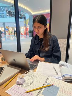 a woman sitting at a table with a laptop computer and headphones in front of her