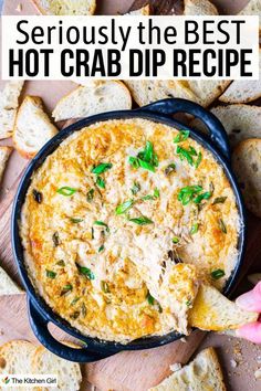 A black dish filled with creamy hot crab dip garnished with green onions, surrounded by toasted bread slices. A hand is dipping a bread slice into the dip. Text at the top reads Seriously the Best Hot Crab Dip Recipe. The Best Crab Dip, Hot Crab Dip Crockpot, Crap Dip Recipe, Crockpot Crab Dip Slow Cooker, Slow Cooker Crab Dip, Imitated Crab Dip Recipes, Hot Crab Dip Recipe With Cream Cheese, Crab Dip Crockpot, Crab Dip Hot