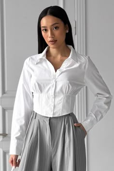 Crop Button Collared Shirt, White Cotton Shirt, Long Sleeve Blouse Top, Fitted Cropped Top, Gifts for Women, Cropped Shirt for Women White basic corset-type shirt. The front part with a corset-type insert, and an elastic band on the back. Silhouette: semi-adjacent Fastening: buttons and loops Neck: shirt Pockets: none Decorative elements: a shaped belt with a "cat's whisker" on the front, and an elastic band insert on the back. Fabric: cotton Composition: 99% cotton, 1% elastane Color: white Siz Shirt Corset, Corset With Sleeves, Corset With Button Down Shirt, Chic Fitted Cropped Shirt With Button Cuffs, Elegant Fitted White Cropped Shirt, Cropped White Collared Shirt, Crop Shirts For Women, Elegant White Button-up Cropped Shirt, White Long Sleeve Cropped Shirt With Button Closure