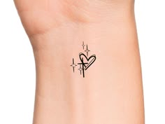 a small heart tattoo on the side of a woman's left arm and wrist