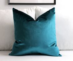 a blue pillow sitting on top of a white couch next to a black framed photograph