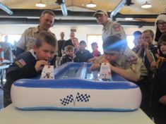 a group of people standing around an inflatable table with two boys playing games on it