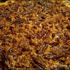 a pie with pecans on it sitting on top of tin foil covered baking pan