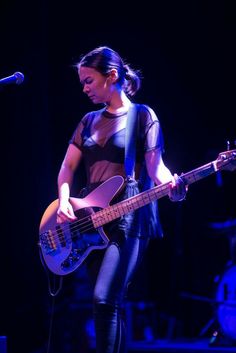 a woman standing on stage with a guitar