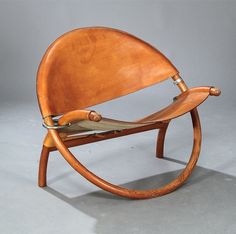 a wooden rocking chair with leather seat and armrests, on a grey background