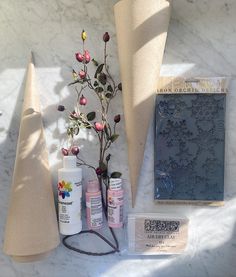 an assortment of crafting supplies are displayed on a white marble counter top, including paper cones and flowers