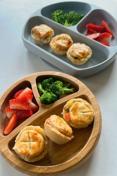 a wooden plate topped with mini pies next to broccoli and strawberries