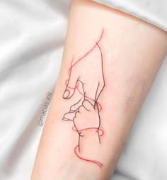 a woman's arm with a red line drawing of a hand holding a baby