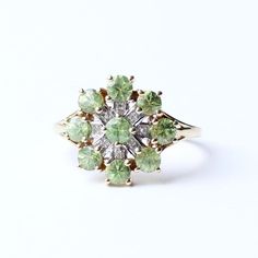 This enchanting 9ct gold ring features a vibrant green zircon at its heart, radiating a natural beauty that captivates the eye. The central zircon is surrounded by a further eight Zircon petals elegantly laid out in a striking star design , giving the ring a bold and sophisticated look. The floral-celestial inspired design adds a touch of grace and femininity, while the shimmering green stone offers a striking contrast against the warm gold band. Perfect for adding a splash of colour to any outfit, this ring combines elegance with a unique, timeless charm. An exceptional piece for those who appreciate refined yet distinctive jewellery. This ring comes presented in a Milly's Marvels gift box. SIZE - US 8 3/4 / UK S (Sizeable) WEIGHT - 2.8grams ERA - Contemporary. HALLMARKS - 375, a lion dat Green 14k Gold Cluster Ring, Vintage Green Diamond Cluster Ring, Vintage Green Diamond Ring Gift, Green Cluster Diamond Ring With Gem, Green Cluster Rings In 14k Gold, Green Cluster Diamond Ring For Anniversary, Vintage Green Diamond Ring With Center Stone, Green Cluster Ring For Anniversary, May Birthstone, Heirloom Green Diamond Cluster Ring