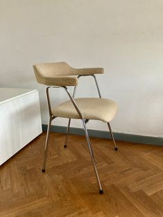 two chairs sitting on top of a hard wood floor next to a white cabinet and wall