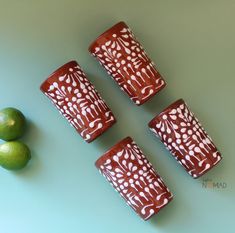 four red and white vases sitting next to limes