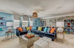 a living room with blue couches and orange pillows