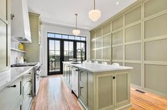 an empty kitchen with wood floors and white counter tops, along with wooden flooring