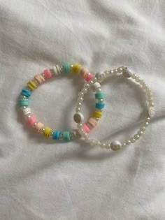 two bracelets with different colored beads on a white sheet