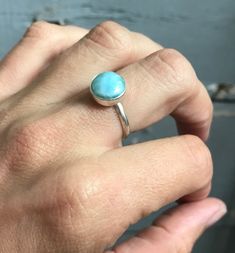 A stunning ethereal sky ocean blue round larimar has been set in sterling silver with a handmade ring band from sterling silver half dome wire. The stone is 11mm round and has interchanging hues of light and white running throughout. Choose your stone from the last photo in the listing. This will be the exact stone used in your ring! Larimar is the embodiment of the tranquil Sea and Sky energies. Its soft, soothing blues and calming turquoise is streaked with white patterns that resemble sunligh Adjustable Blue Larimar Ring, Turquoise Moonstone Ring In Sterling Silver, Blue Larimar Round Rings, Turquoise Larimar Cabochon Jewelry, Silver Amazonite Round Jewelry, Adjustable Larimar Turquoise Ring, Adjustable Turquoise Larimar Ring, Turquoise Larimar Round Ring, Turquoise Larimar Ring