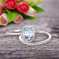 an oval blue topaz ring sits on a table next to tulips