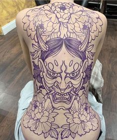 the back of a woman's body is covered in tattoos with flowers on it