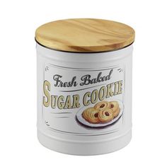 a white canister with a wooden lid filled with sugar cookies on the front and side