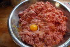 a metal bowl filled with meat and an egg