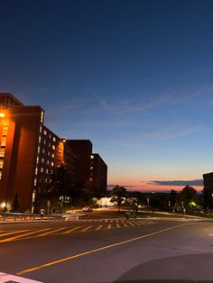 an empty street at night with buildings in the background