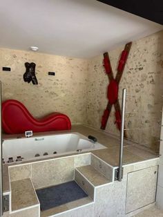 an indoor jacuzzi tub with stairs leading up to it and a red chair in the corner