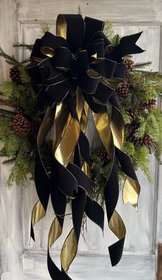 a black and gold bow hanging from the side of a door with pine cones on it