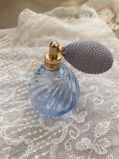 an empty blue bottle sitting on top of a white lace covered table cloth next to a silver object