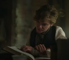 a young man sitting at a table reading a book