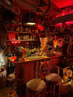 a bar with stools and various decorations on the shelves in front of it is lit up by red lights