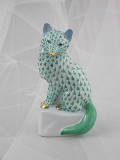 a green and white cat figurine sitting on top of a table