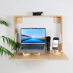 an open laptop computer sitting on top of a wooden shelf next to a cell phone