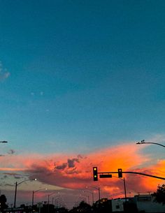 the sun is setting over an intersection with traffic lights and street signs on both sides