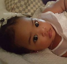 a baby laying on top of a bed next to a teddy bear