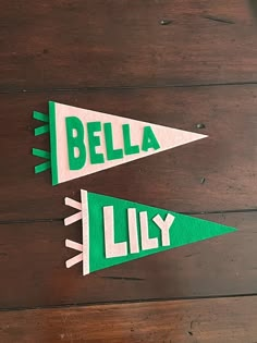 two green and white paper pennants with the words bella lily on them sitting on a wooden surface