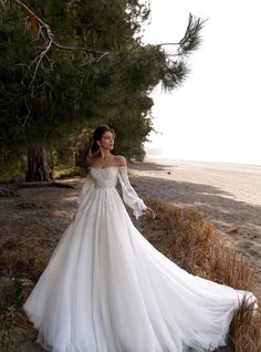 a woman in a wedding dress standing on the beach