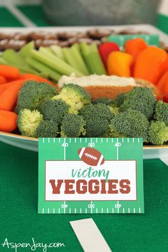 a football themed veggie platter on a green tablecloth with a name tag